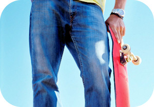 Low section of a male skateboarder holding his skateboard